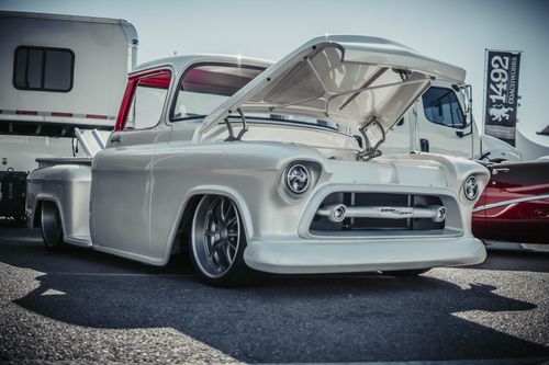 Free Vintage pickup truck with open hood displayed at an outdoor car show, showcasing its custom modifications. Stock Photo