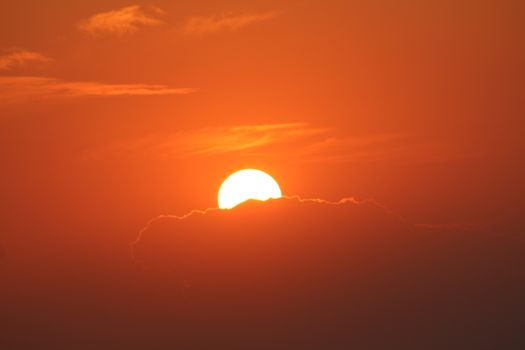 Stunning sunset with a vibrant orange sky and silhouetted clouds. Ideal for nature themes.