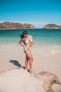 Woman in bikini with sunglasses enjoying sun on a beautiful beach. Perfect summer vibes.