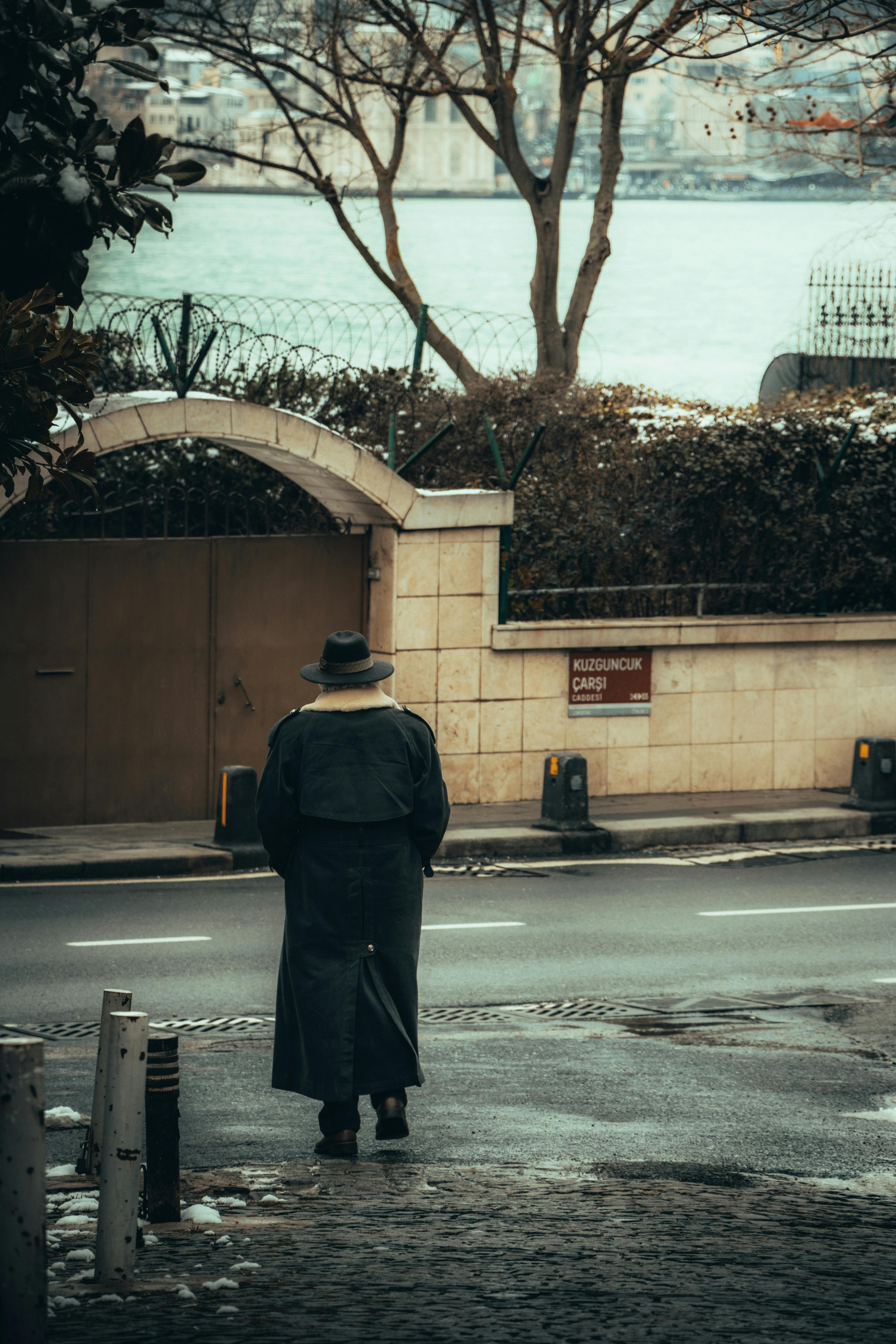 person in coat and hat walking on street