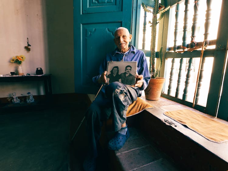 Elderly Man Holding Couple Photograph