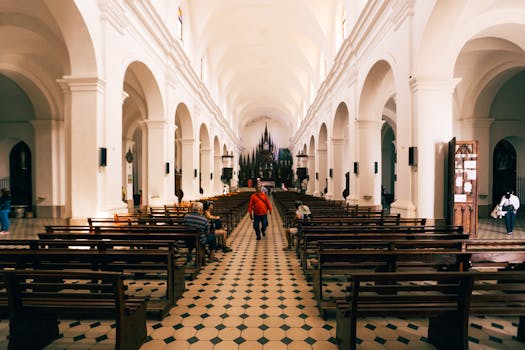 Wide-angle view of a church interior, showcasing elegant arches and pews in a serene setting.