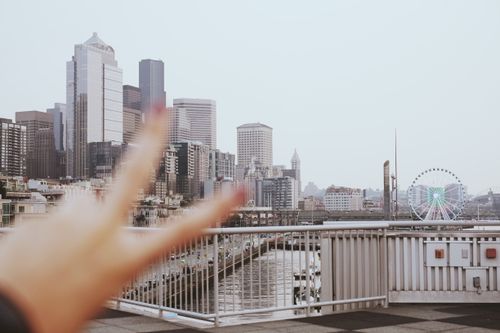 Free A vibrant Seattle skyline view featuring modern architecture and a Ferris wheel with a peace sign gesture in the foreground. Stock Photo