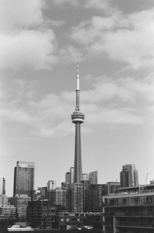 Free Black and white photo of Toronto's CN Tower and urban skyline under cloudy skies. Stock Photo