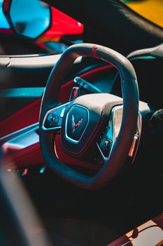Close-up of a sleek car steering wheel with elegant design details in bright lighting.
