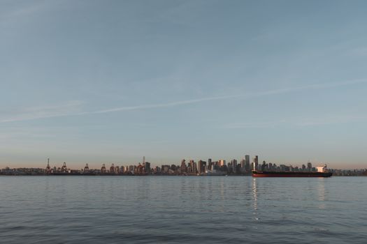 Vancouver's city skyline with a ship on calm waters during sunset.