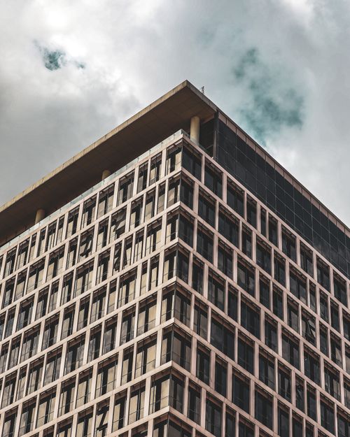 Free Low angle view of a modern high-rise building with grid windows against an overcast sky. Stock Photo
