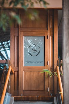 Elegant wooden emergency exit door with a glass panel in an outdoor setting.
