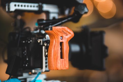 Free Close-up of a wooden camera rig handle with blurred background, showcasing modern filming equipment. Stock Photo
