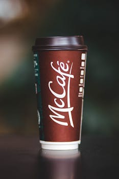 Elegant close-up shot of a McCafé coffee cup with logo in warm tones.