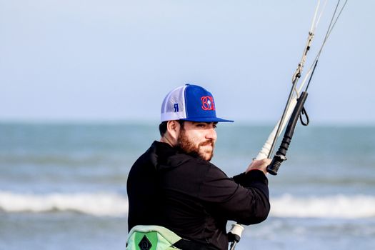 Man in Black Jacket and Green and White Shorts Holding Black and Brown Fishing Rod