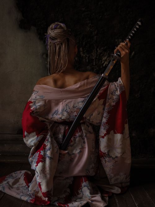 Free Back view of a woman in a kimono holding a sword, symbolizing tradition and mysticism. Stock Photo