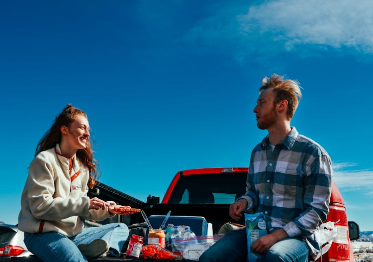 Man And Woman Sitting On The Back Of A Pick Up Truck