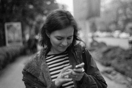 Grayscale Photo of Woman Holding a Mobile Phone