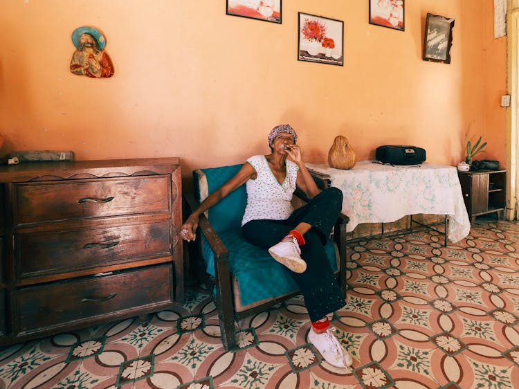 Woman In Head Covering Sitting In Armchair With Ankle On Knee