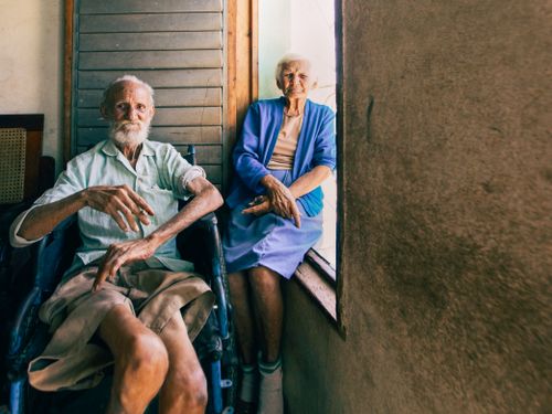 Free An elderly couple sitting by a window, capturing a serene moment indoors with natural light. Stock Photo