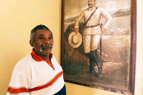 Free An elderly man stands beside a historical painting of a soldier, indoors. Stock Photo