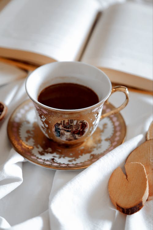 Cup of Coffee with an Open Book in the Background