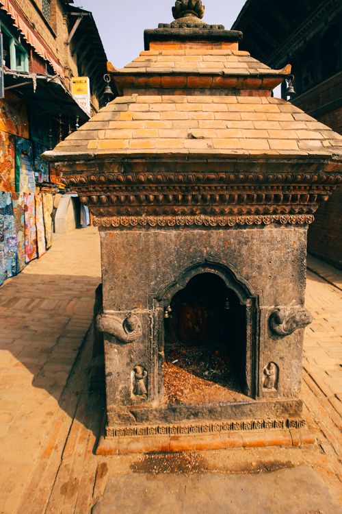 Free A traditional stone shrine with intricate carvings on a bustling city street. Stock Photo