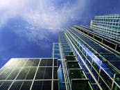 低角度镜头下的现代摩天大楼，反光玻璃窗映衬着清澈的蓝天