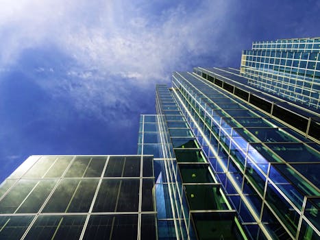 低角度镜头下的现代摩天大楼，反光玻璃窗映衬着清澈的蓝天