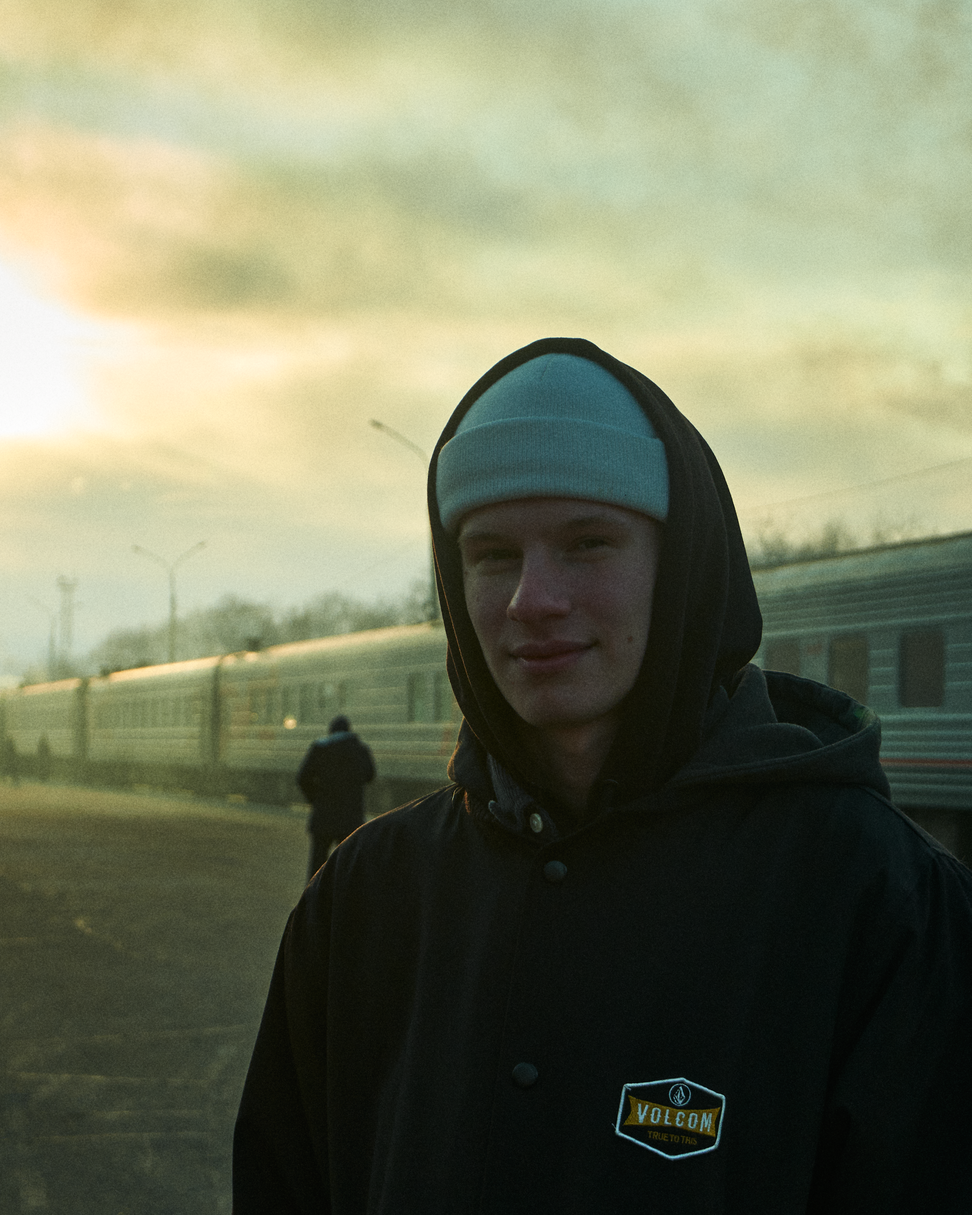 Young man smiling at a train station in Komsomolsk-on-Amur, Russia during sunset.