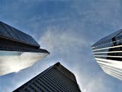 现代摩天大楼在低角度视角下，将阳光反射到清澈的蓝天上