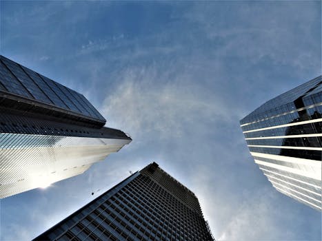 现代摩天大楼在低角度视角下，将阳光反射到清澈的蓝天上