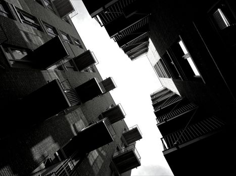 A low angle view of modern buildings with balconies in dramatic black and white contrast.