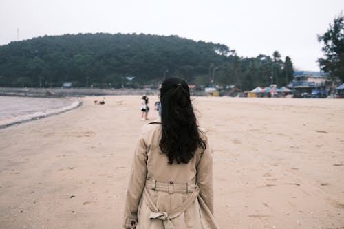 Free Woman in Brown Coat Standing on the Beach Stock Photo