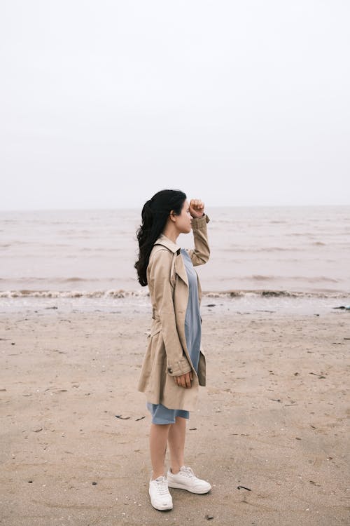 Free Woman in Beige Coat Standing on Beach Stock Photo