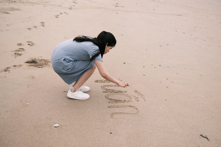 Woman Writing On Sand