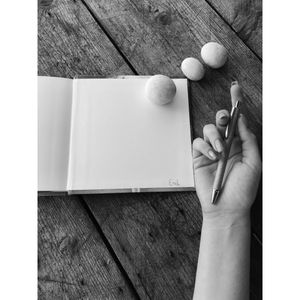 Hand holding a pen over an open notebook — photo by Dina Creative on Pexels