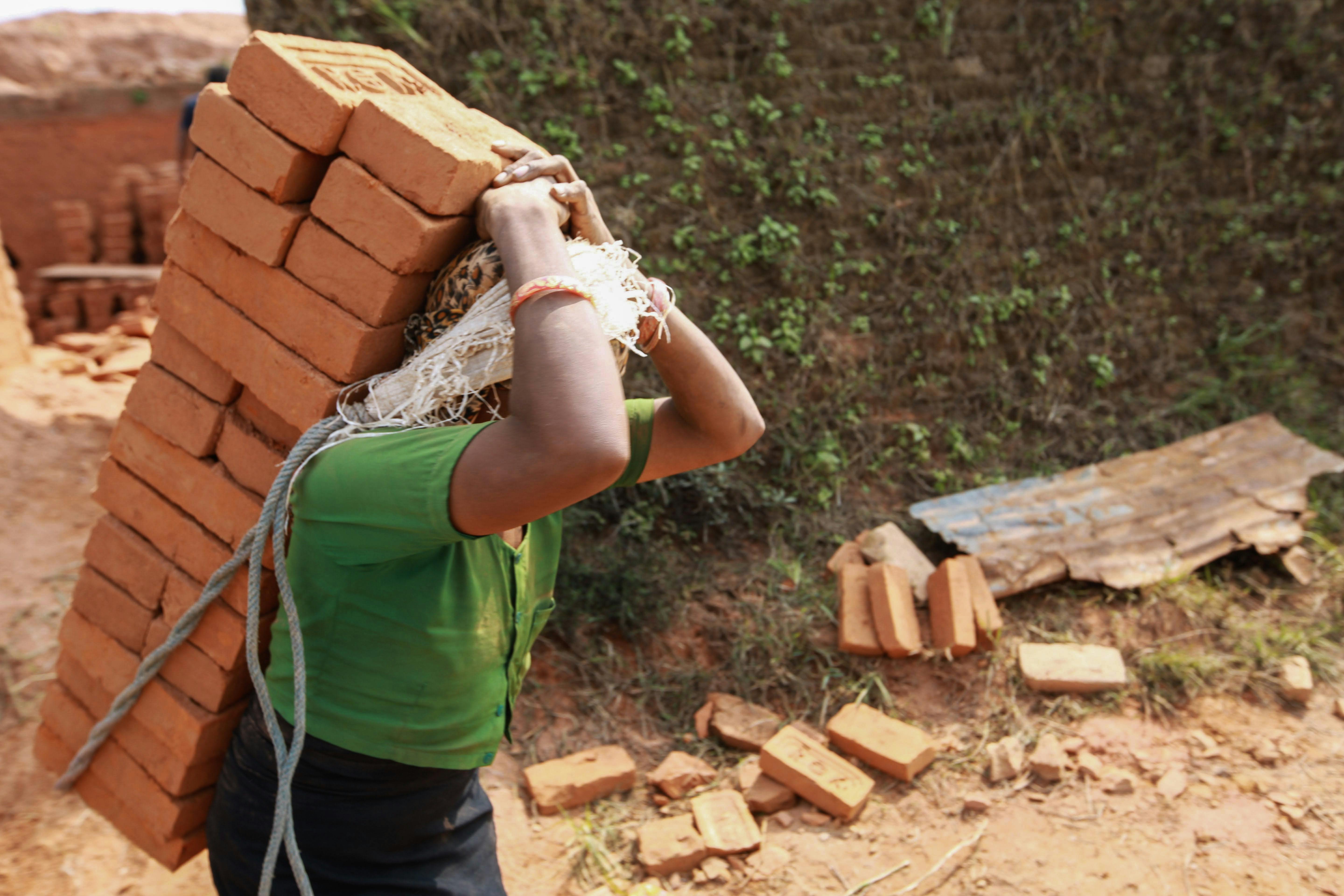A Person Carrying Bricks on Back while Working · Free Stock Photo