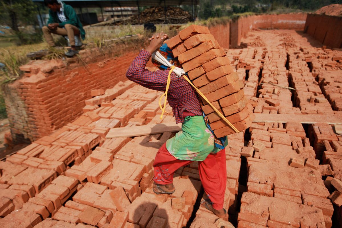 A worker carrying stacked bricks on his back in South Asia