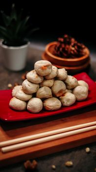 Stack of homemade dumplings on a red plate with chopsticks, highlighting Asian cuisine. - Fotografer Sidoarjo