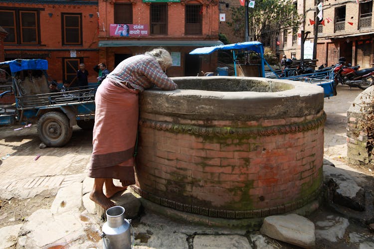 An Elderly Person Looking Down On A Well