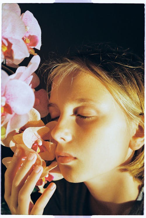 Close Up Photo of Girl's Face Near Flowers