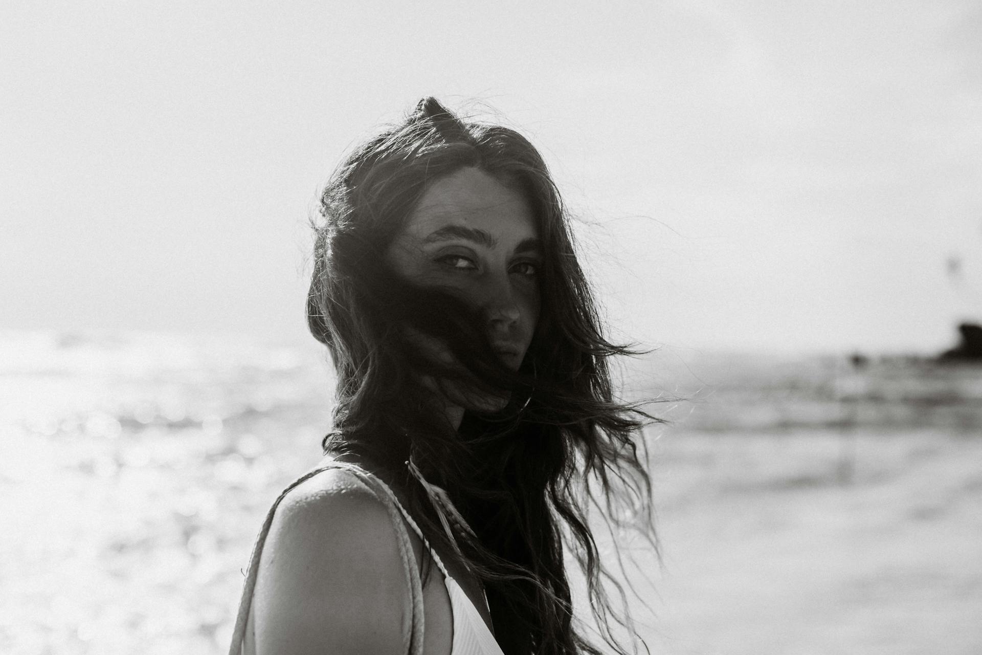 A striking black and white portrait of a woman with windswept hair on a Sri Lankan beach.