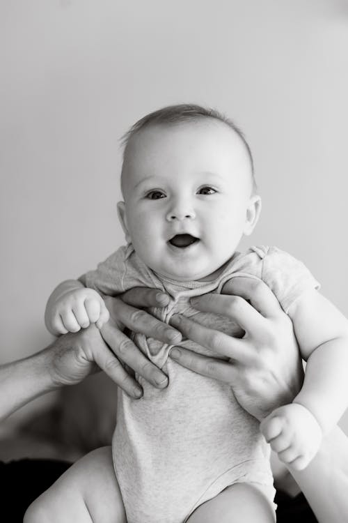 Free A Black and White Picture of a Baby in Onesie Carried by a Person Stock Photo