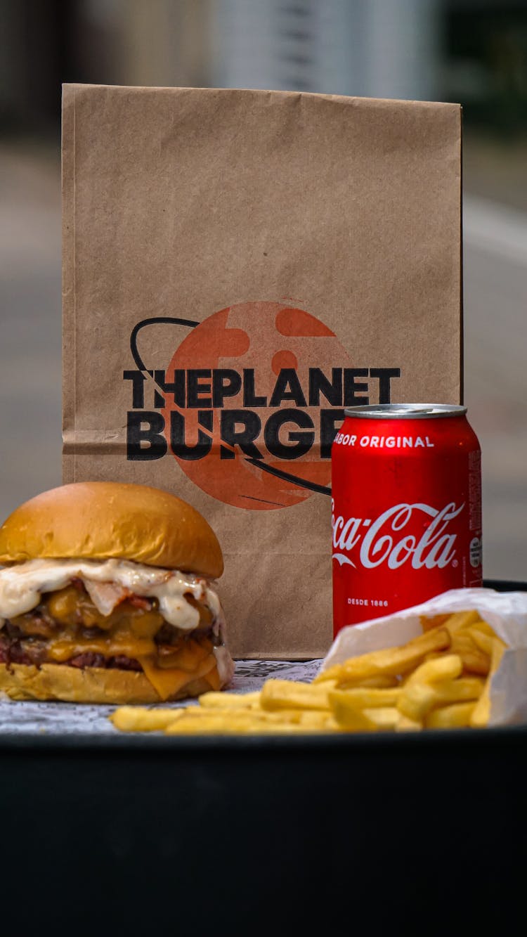 Burger Sandwich And Fries Beside A Soda Can And Paper Bag