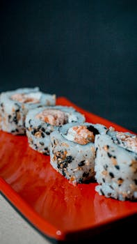 Appetizing sushi rolls on a vibrant red plate, perfect for culinary enthusiasts.