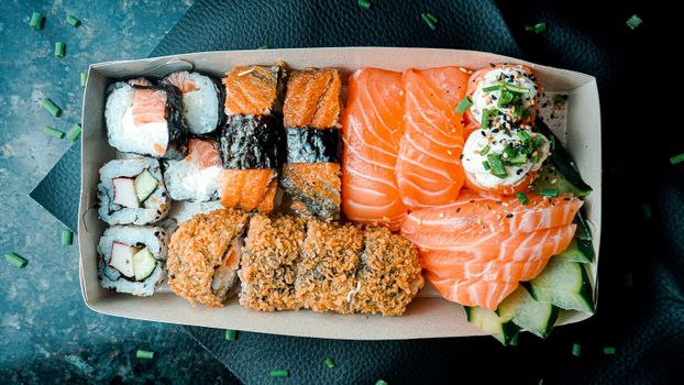 A vibrant box of sushi and sashimi featuring salmon and tuna, perfect for food lovers.