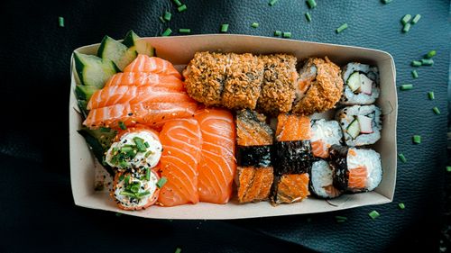 Free A mouth-watering assortment of sushi featuring nigiri, sashimi, and rolls in a takeout box. Stock Photo