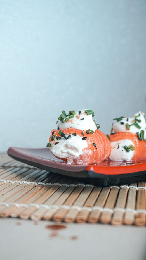 Free Close-up of salmon sushi rolls with cream cheese and chives on a plate, enhancing Japanese cuisine's appeal. Stock Photo
