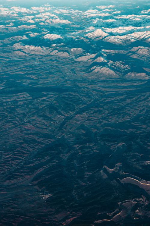 Free A breathtaking aerial shot showcasing majestic snow-capped mountains stretching into the horizon. Stock Photo