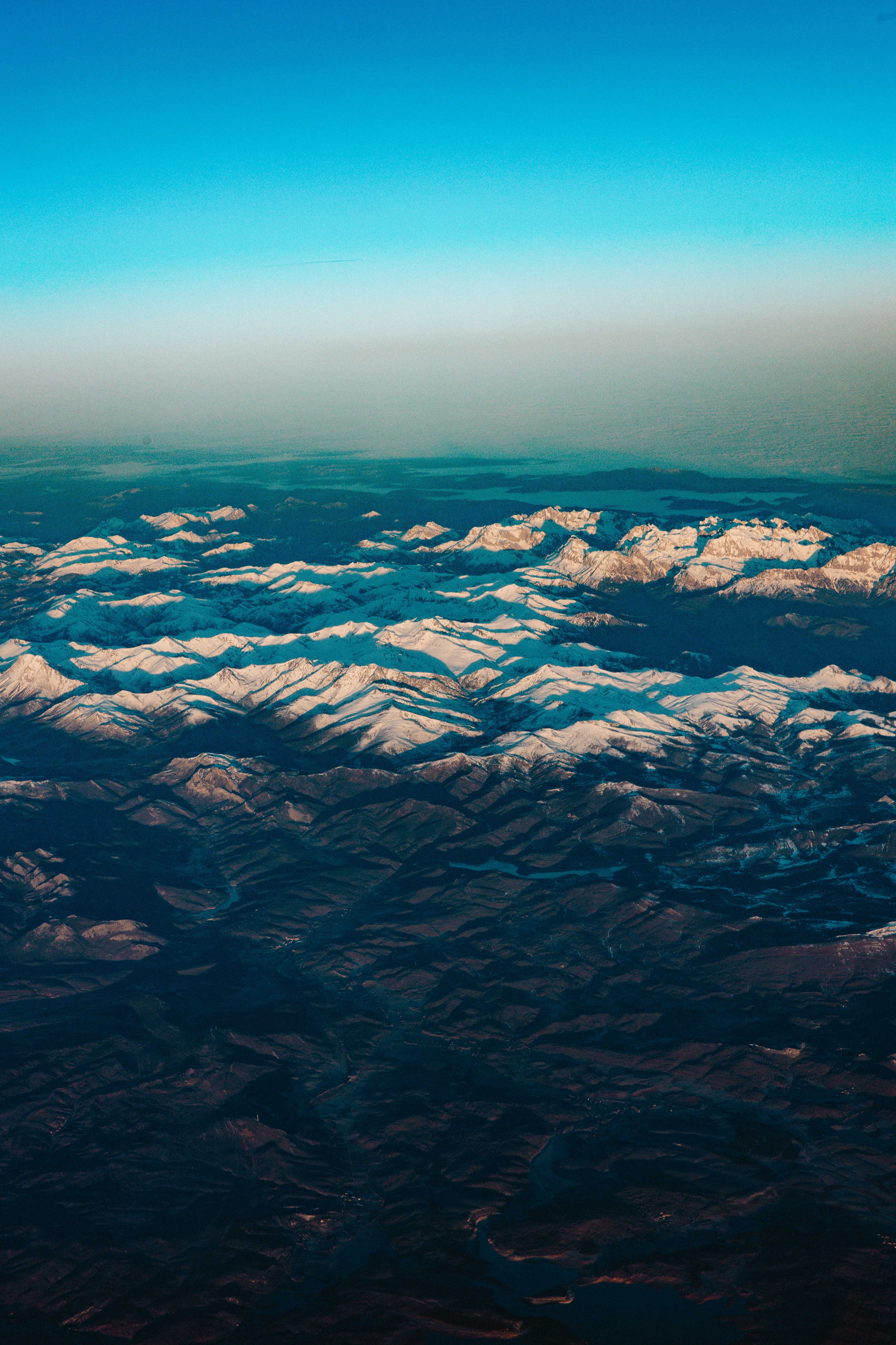A breathtaking aerial view of snow-capped mountains under a clear sky, showcasing nature's beauty.