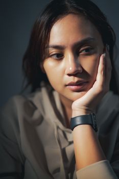 Close-up portrait of a thoughtful woman resting her chin on her hand.
