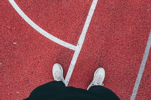 White sneakers and track lines on a red athletic surface, a dynamic sports moment.