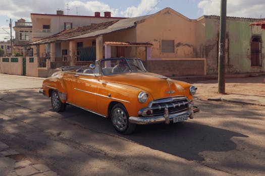 A classic orange convertible parked on a sunny urban street corner, evoking nostalgia.